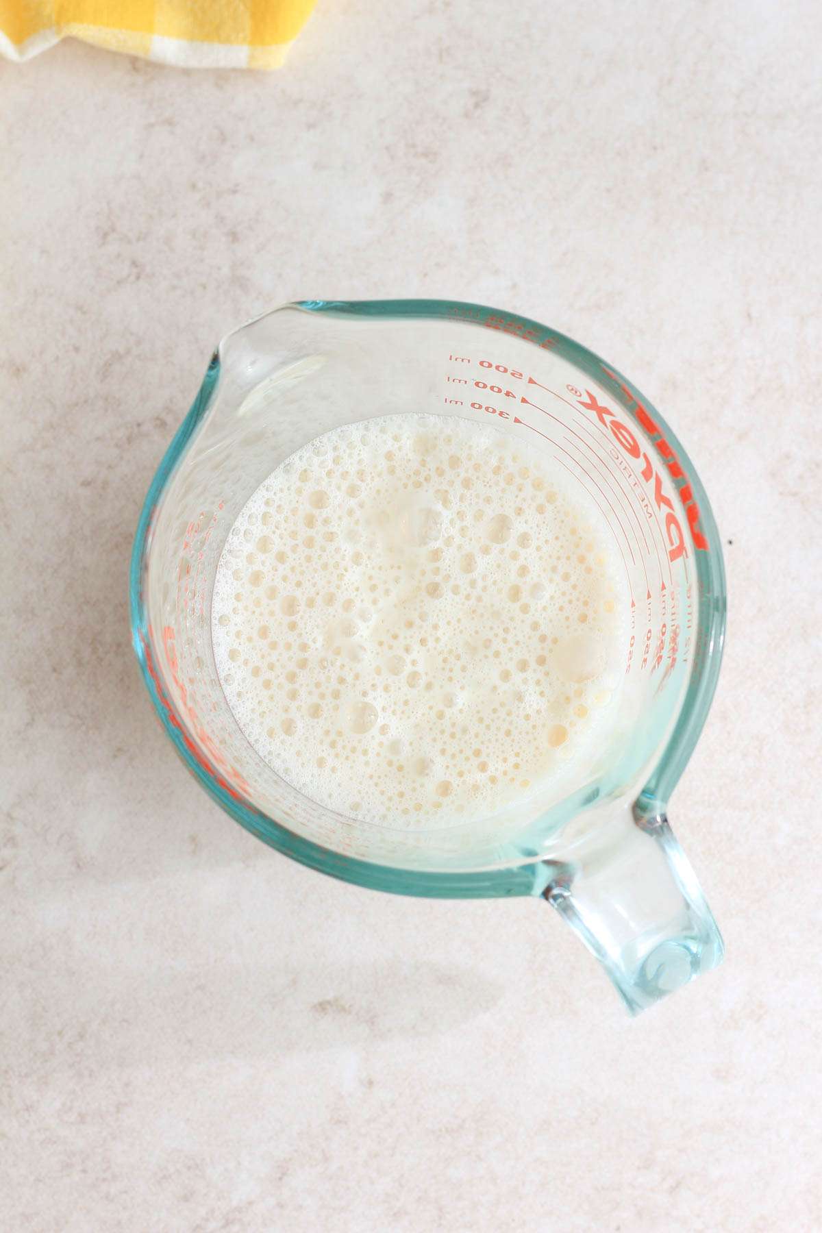 A top down image of vegan buttermilk in a liquid measuring cup.