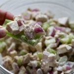 Bowl of chicken salad with a scoop on a piece of celery.