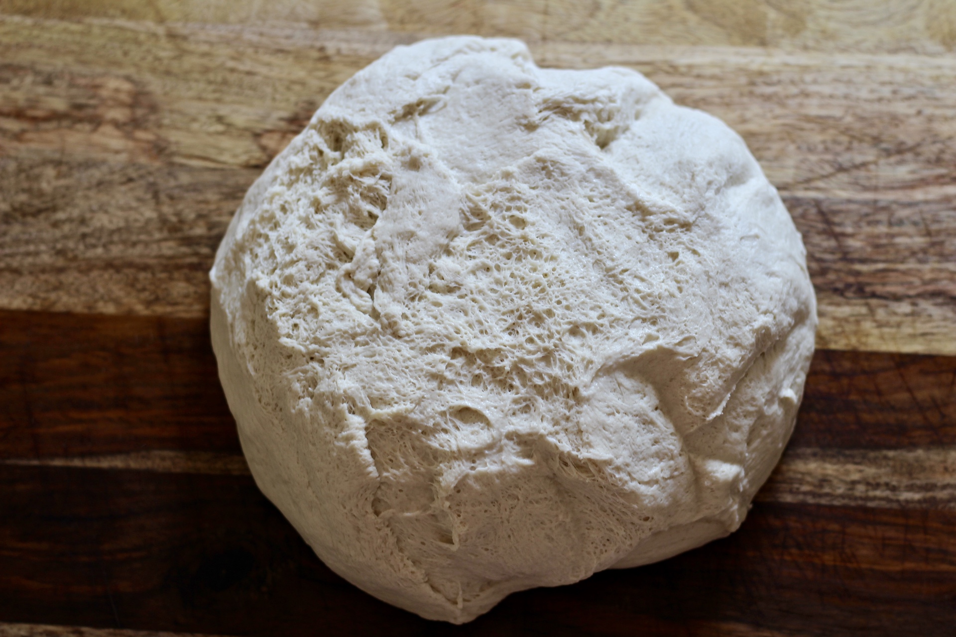 Soft dough on a wooden cutting board.
