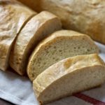 Sliced bread on a white and red dish towel.