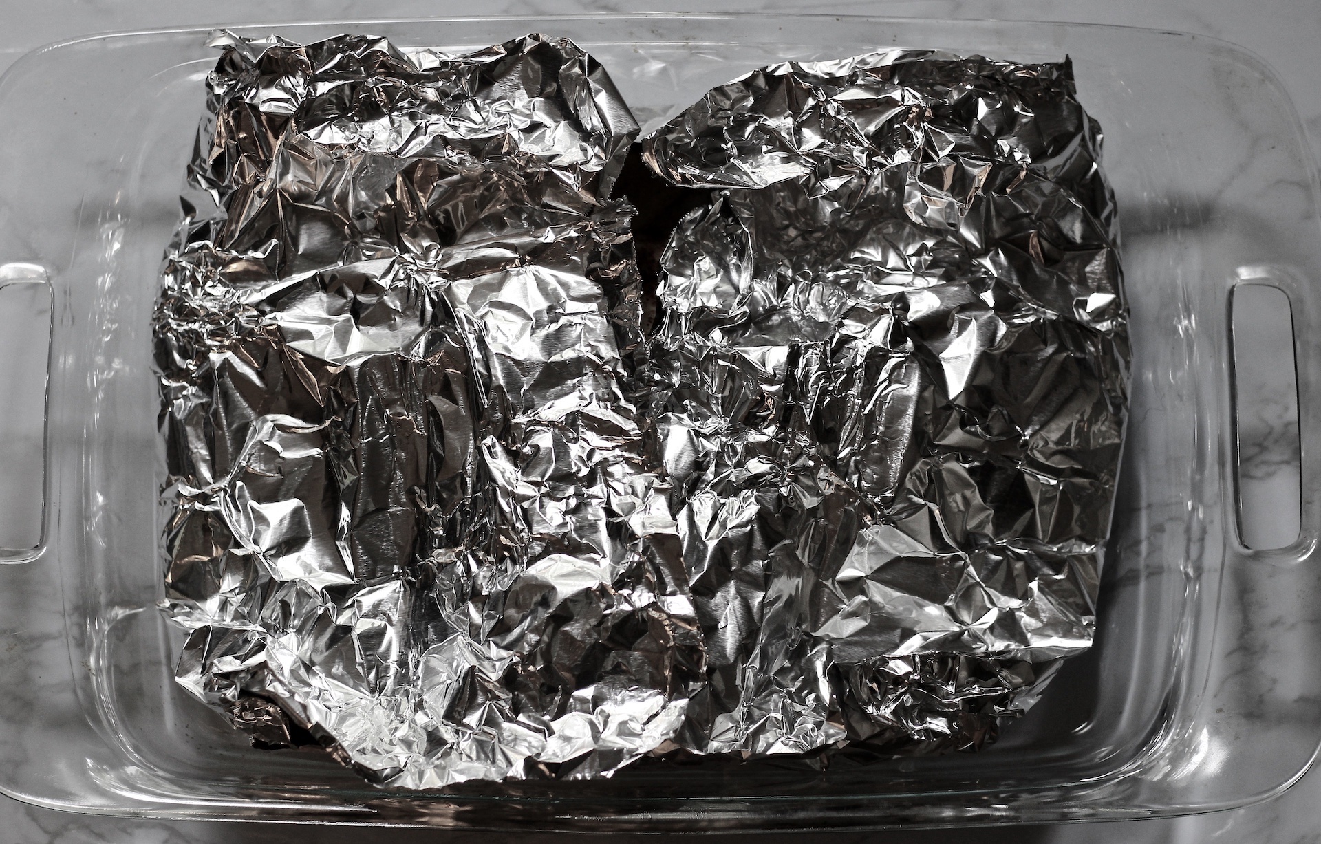 Foil covering the oven baked chicken breasts.