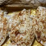 Baked chicken in the dish with foil and juices.