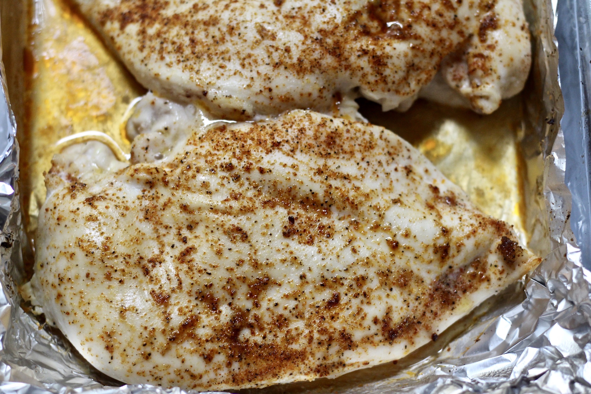 Baked chicken breasts in foil with juices.
