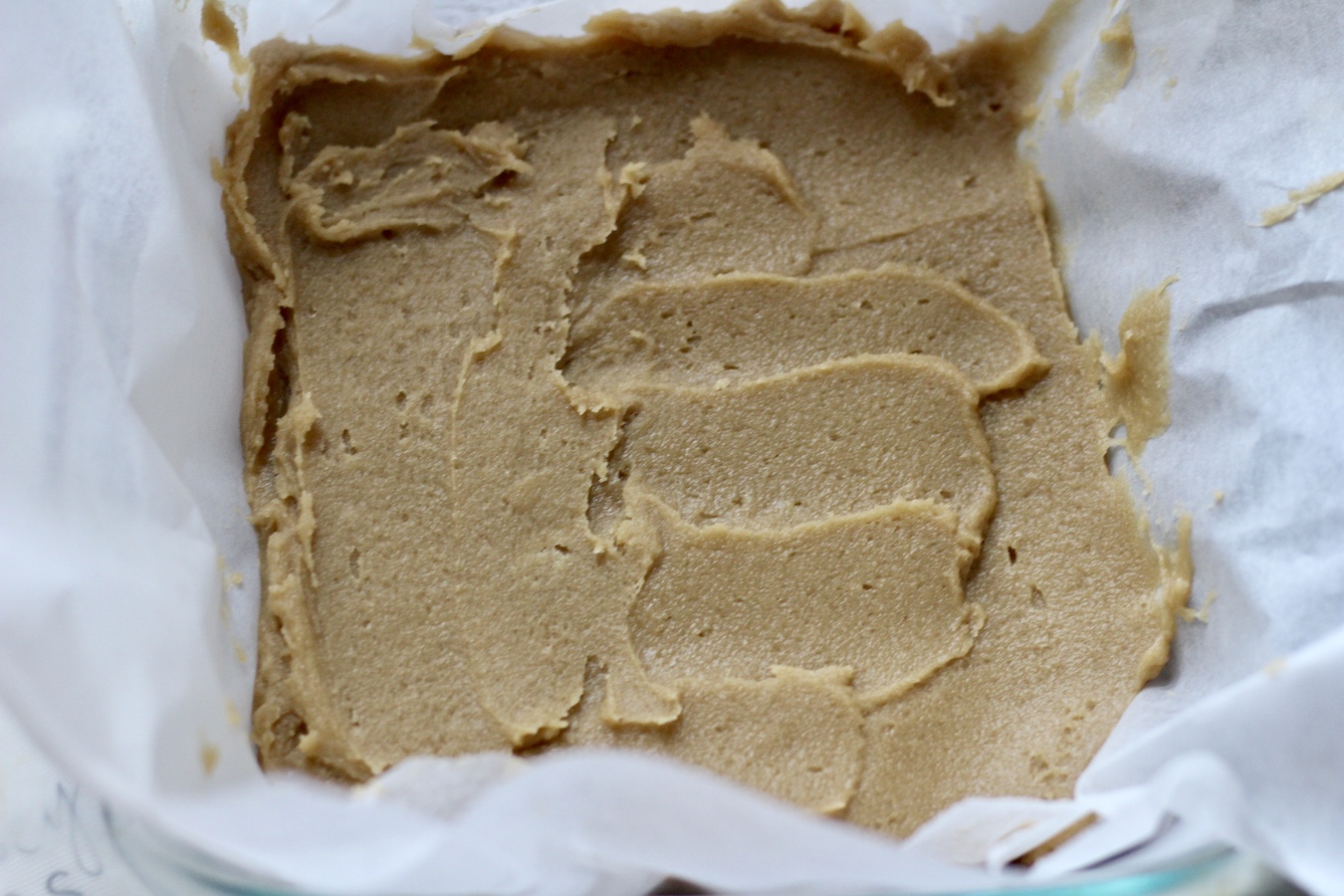 Blondie base spread into the baking dish covered with parchment paper.