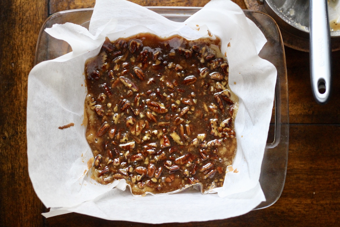 Pecan Pie Blondies in the pan before baking with a saucepan in the top right corner.