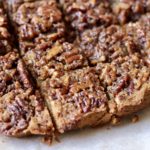 Cut pecan pie blondies on a parchment paper on a wooden cutting board.
