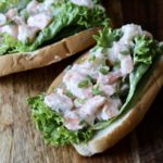 Two shrimp rolls on a wooden cutting board.