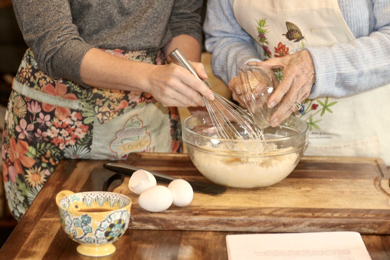 Annie and Grandma making chess pie together on a wooden table.
