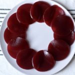 A white plate of sliced cranberry sauce on a white and blue dish towel.