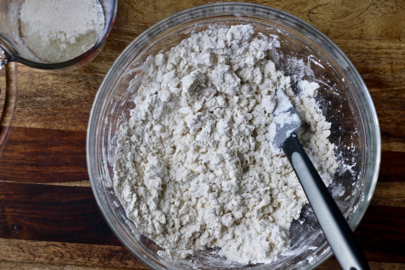 Biscuit dough in a glass bowl with nondairy milk being stirred in.