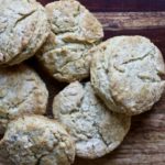 Six garlic and herb biscuits in a pile on a wooden cutting board.