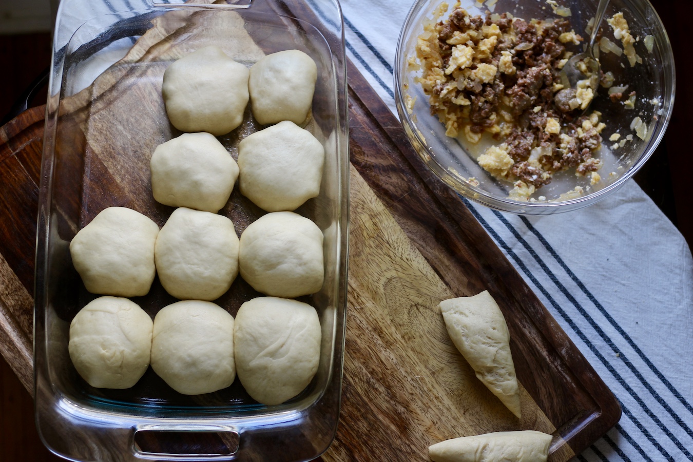 Sausage and egg kolaches in a pyrex dish with the sausage and egg filling on the right and a dough triangle in the bottom.
