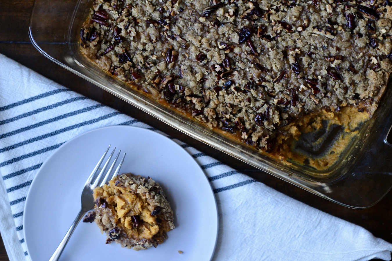 Sweet potato casserole in a pyrex dish with a small plate of sweet potato casserole in the front.