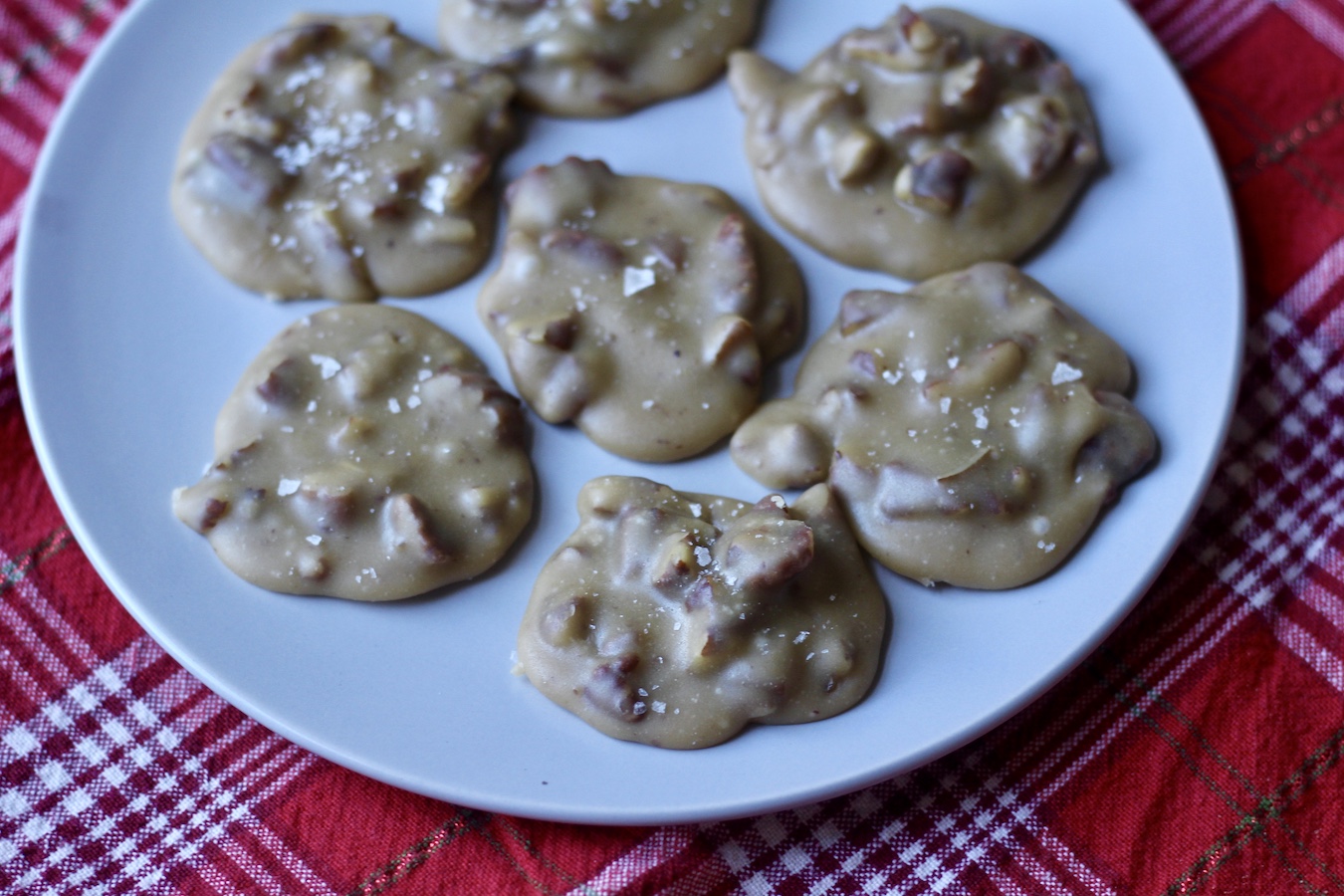 Small white plate with 7 pralines on a red checkered dish towel.