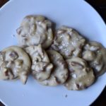 White plate with pecan pralines on a wooden table.