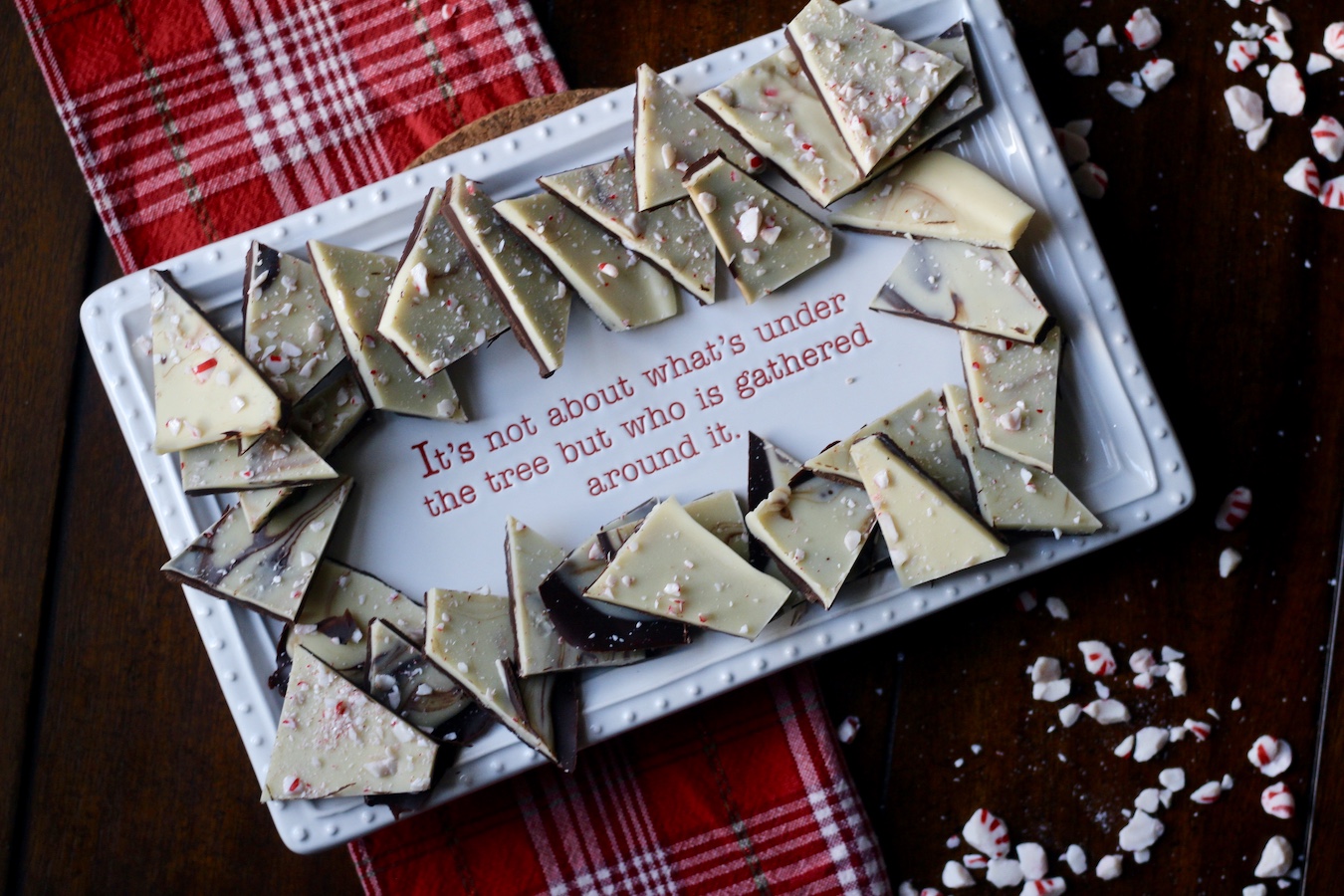 A platter that says It does not matter what is under the tree but who is gathered around it with peppermint bark on the platter.