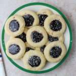 A close up of a white and green plate with dairy-free spiced blackberry thumbprint cookies.