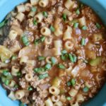 A blue bowl of turkey mac on a wooden counter.