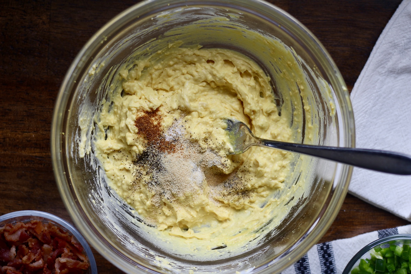 A glass bowl with deviled egg filling mixed together on a wooden table.