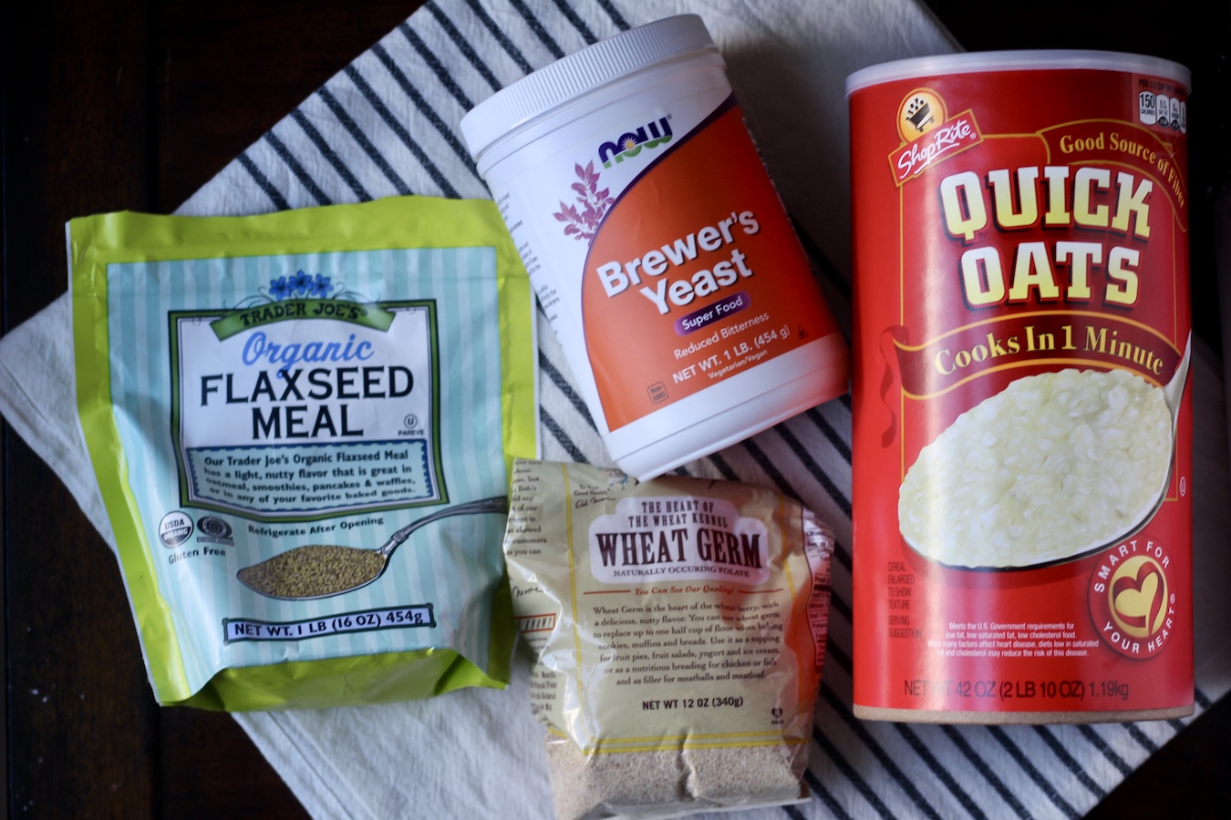 Flaxseed meal, brewer's yeast, wheat germ, and oatmeal on a white and blue dish towel.