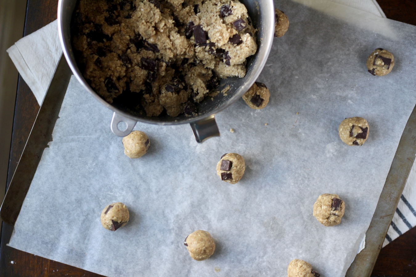 Lactation cookie dough in a silver bowl with 1o balls on a cookie sheet with parchment paper.