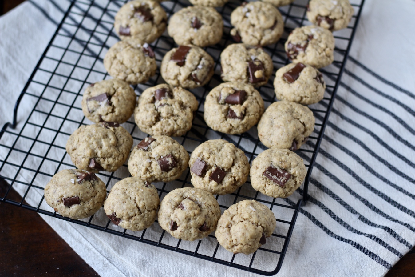 Baked lactation cookies on a cooling rack on a white and blue striped dish towel.