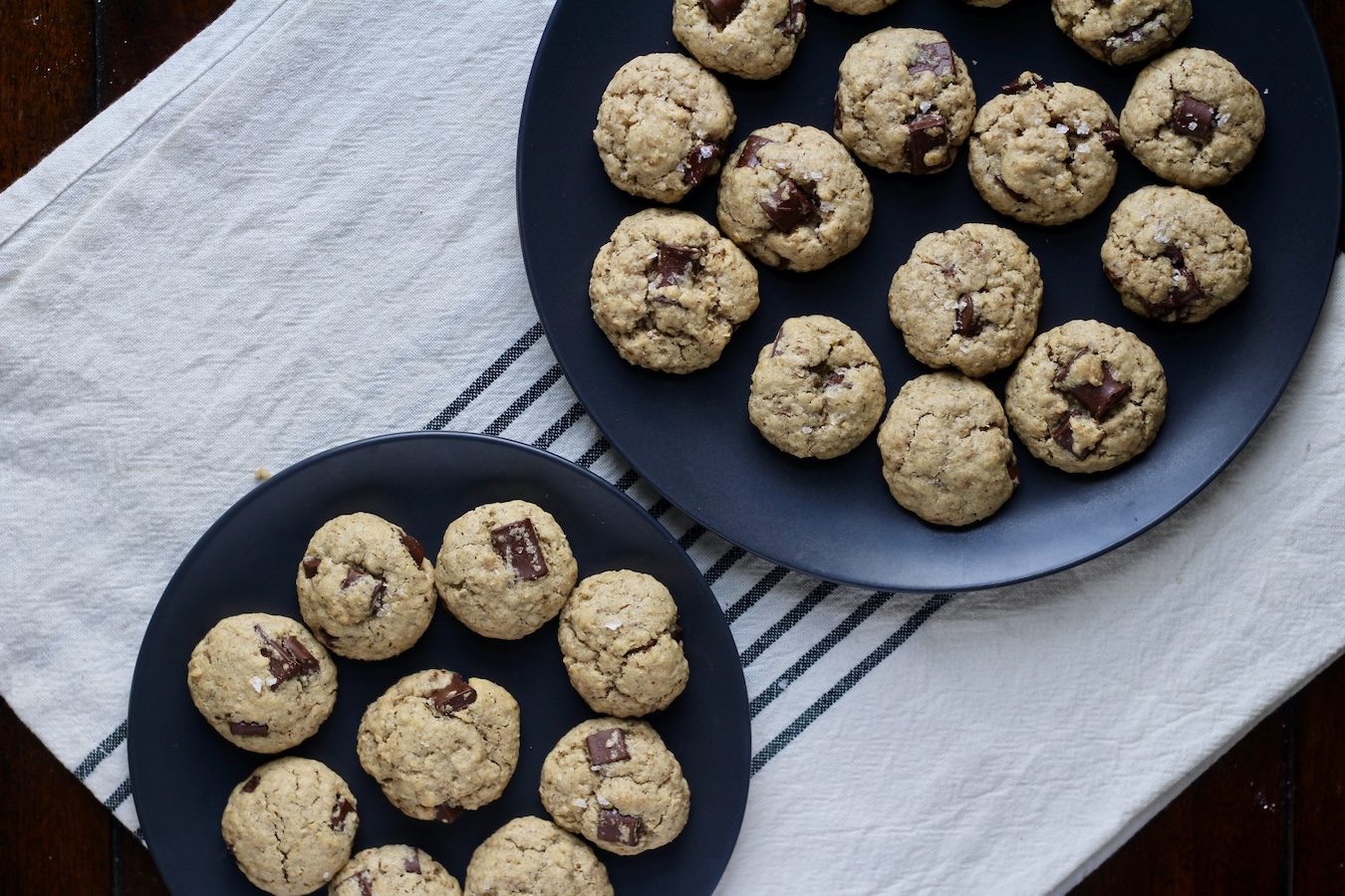 Two blue plates with lactation cookies on a white and blue striped dish towel.