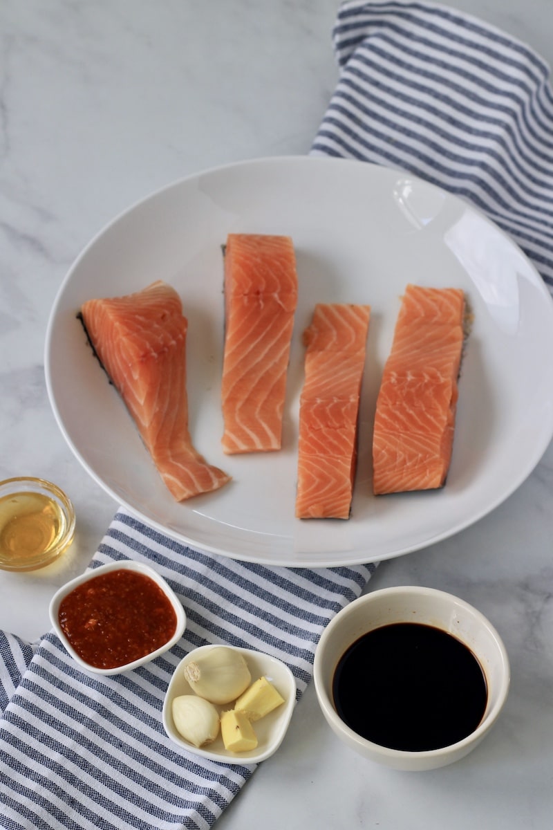 Ingredients for salmon avocado bowls on a counter with a blue and white striped towel.