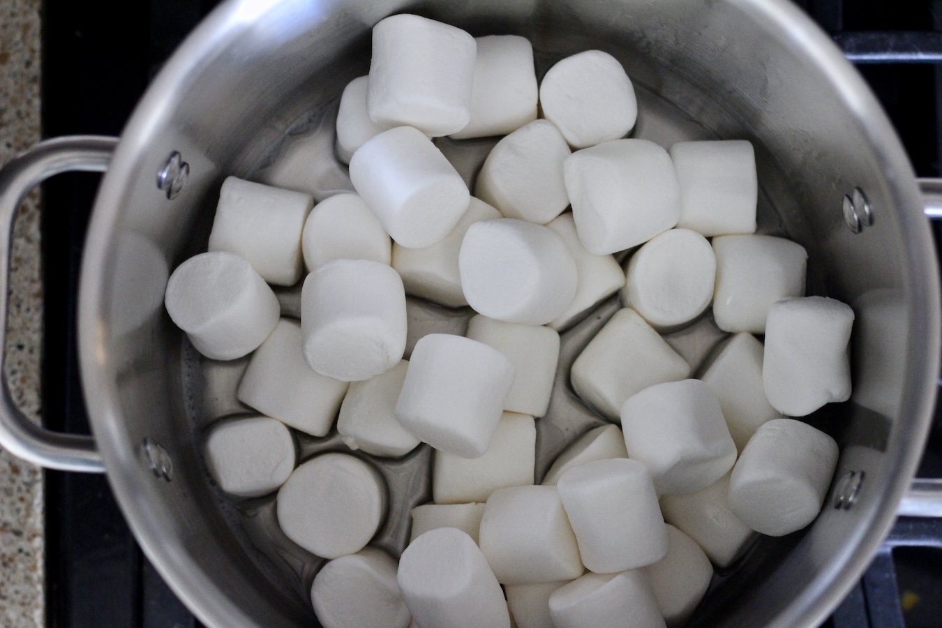 A stainless steel pot with coconut oil and marshmallows melting.