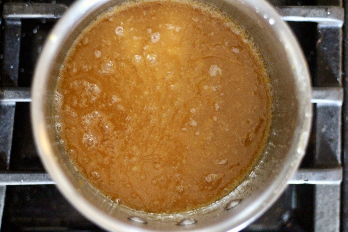 Melted butter and sugar boiling in a silver pot on a stove.