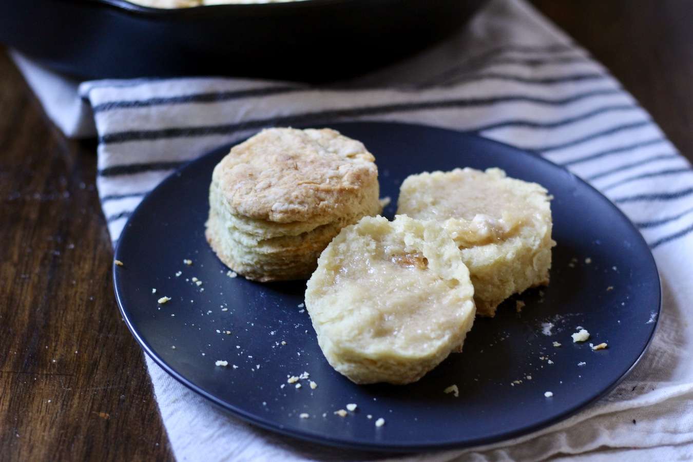 A blue plate with two skillet biscuits on a white and blue dish towel on a wooden table.