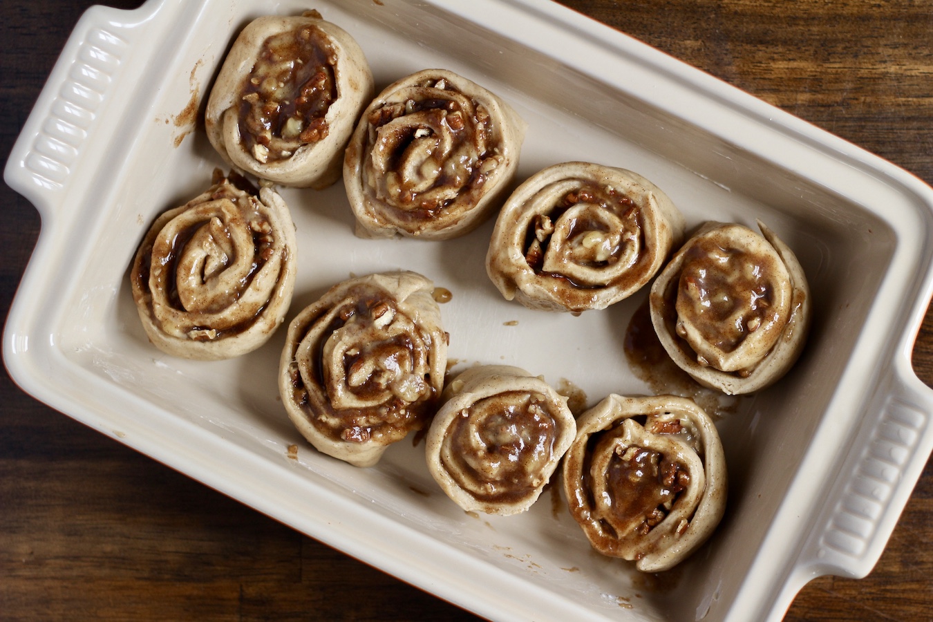 8 uncooked cinnamon rolls in a baking pan.