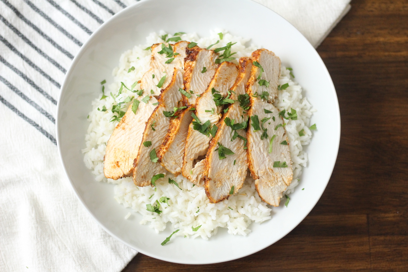 A white bowl with rice and southwest chicken on a white and blue striped towel.