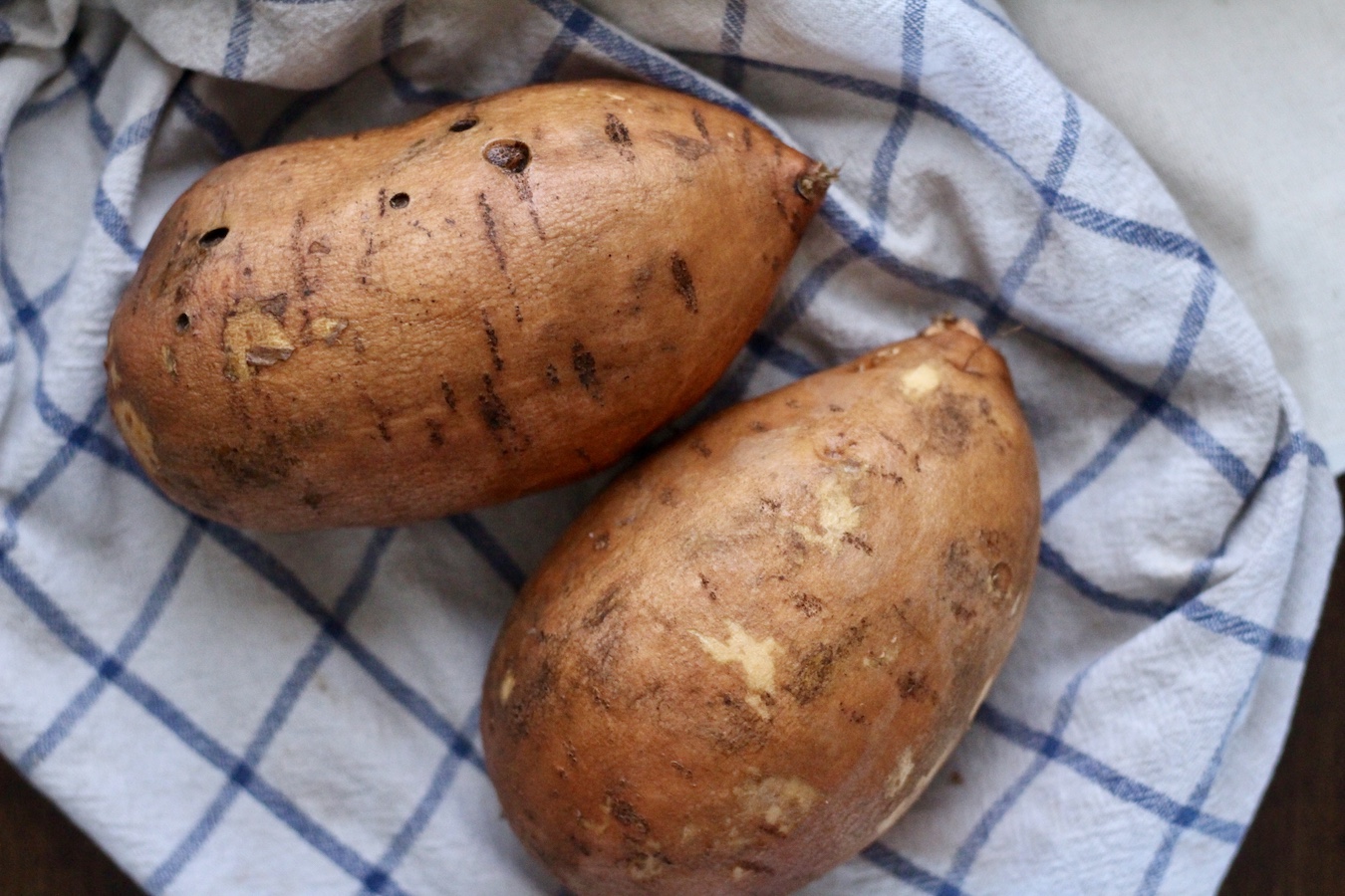 Washed sweet potatoes on a blue and white dish towel.