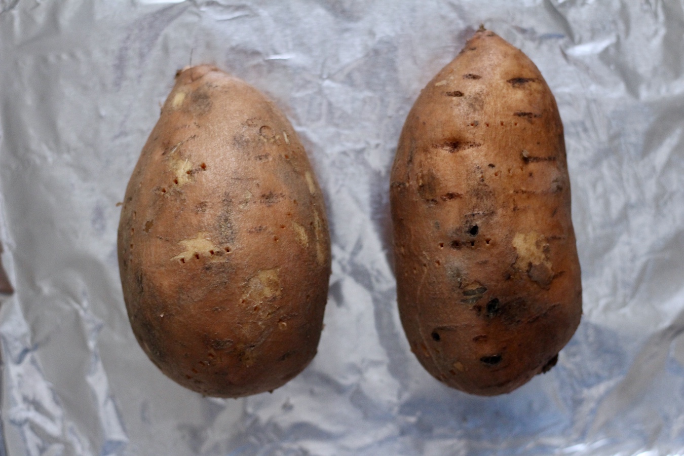 Washed and poked sweet potatoes on a foil lined baking sheet.
