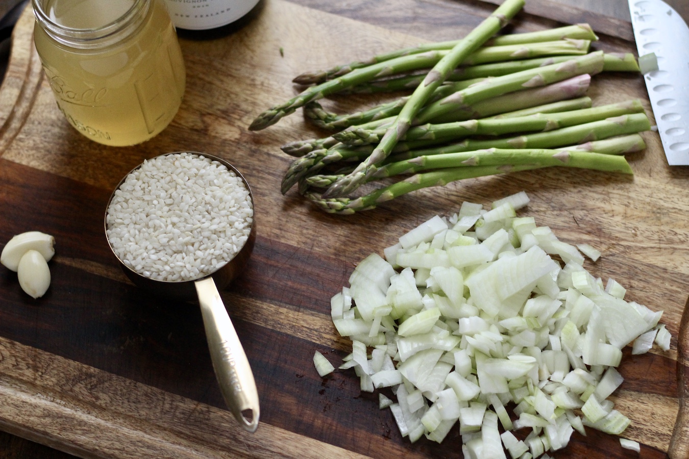Ingredients for asparagus risotto on a wooden cutting board.