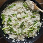 Finished asparagus risotto in a non-stick skillet with a wooden spoon.