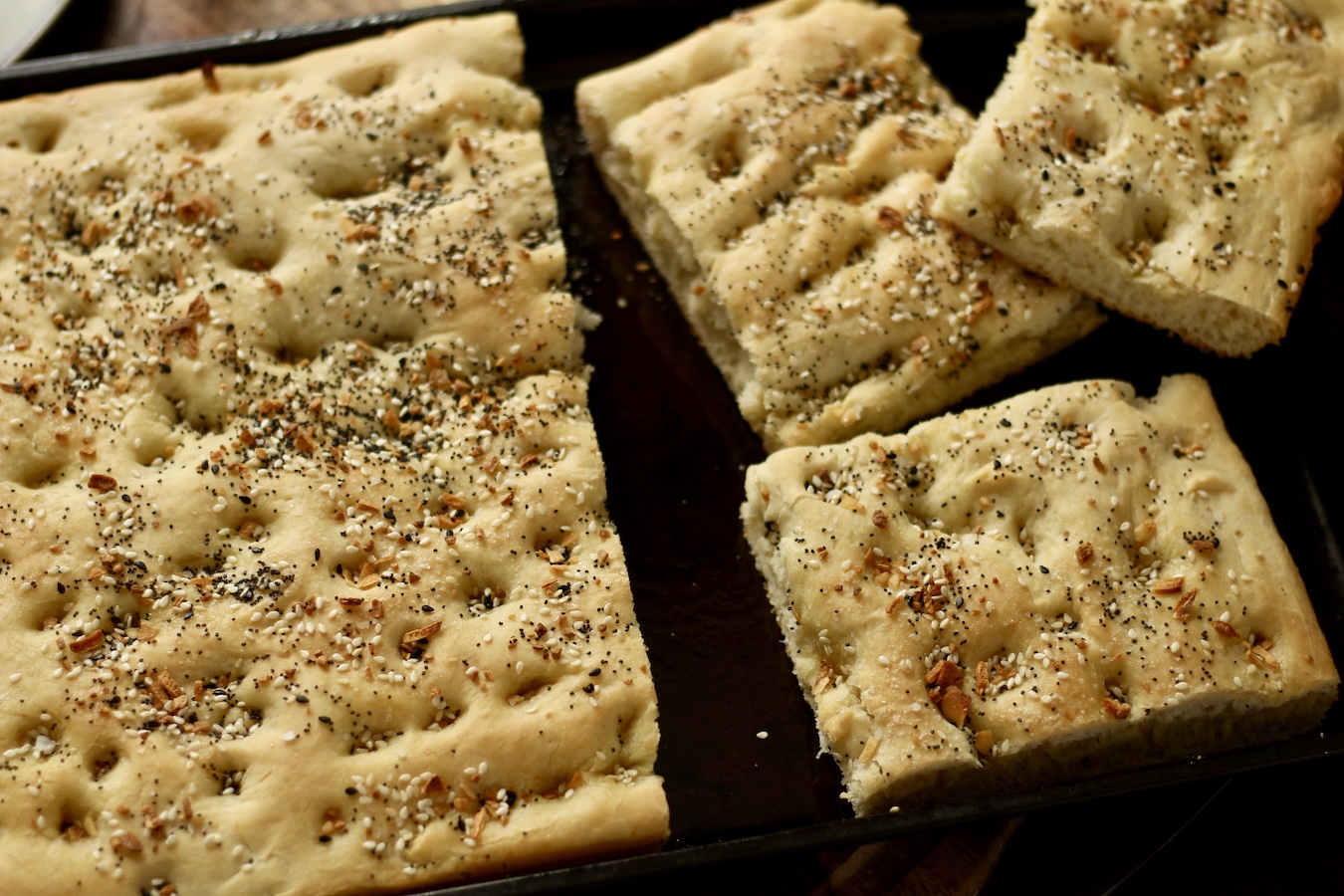 Breakfast Focaccia cut into 3 squares on the right of the baking sheet with the remaining uncut focaccia on the left.