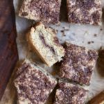 Cut cinnamon crumble bard on a parchment paper on a wooden cutting board.