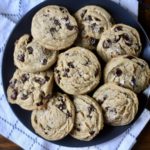 Egg free chocolate chip cookies on a blue plate with a white and grey dish towel under the plate.