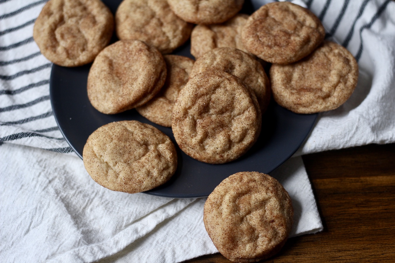 A blue plate full of snickerdoodle cookies on a white and blue dish towel.