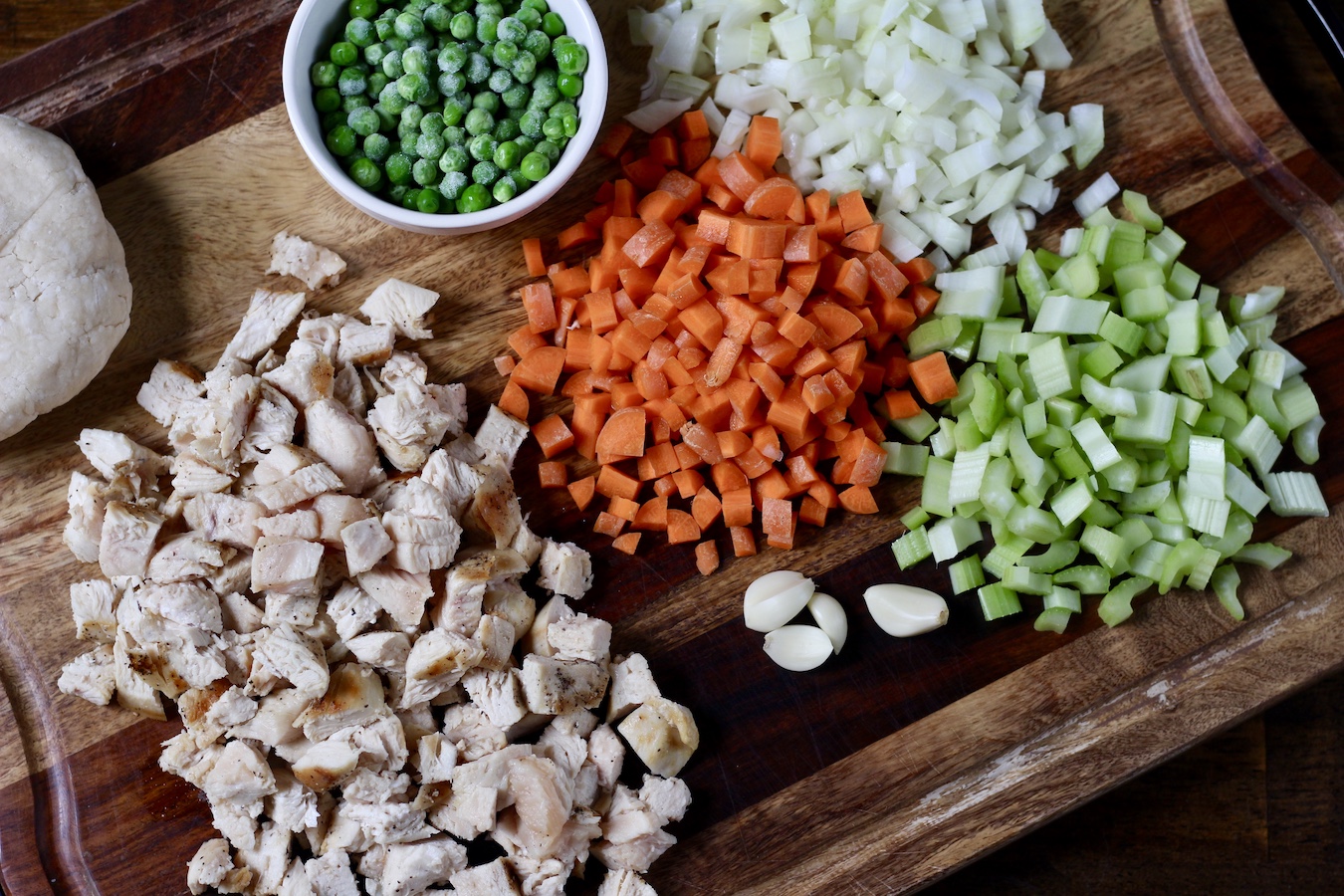 Chopped ingredients on a cutting board for chicken pot pie.