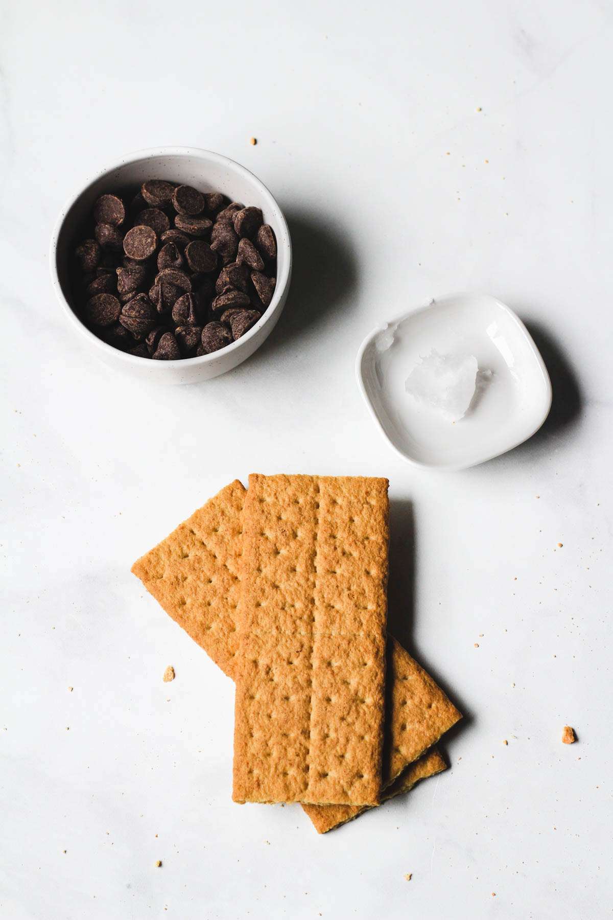 Ingredients for dark chocolate dipped graham crackers on a white counter.