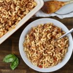 A bowl of hamburger helper with a baking dish of hamburger helper in the top left.