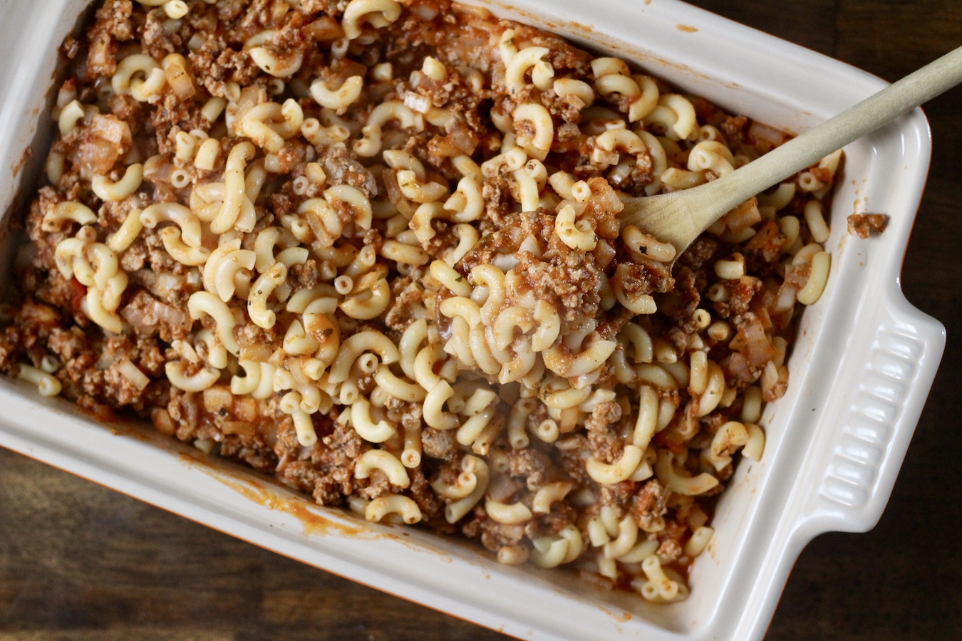 Homemade hamburger helper in a baking dish with a wooden spoon.
