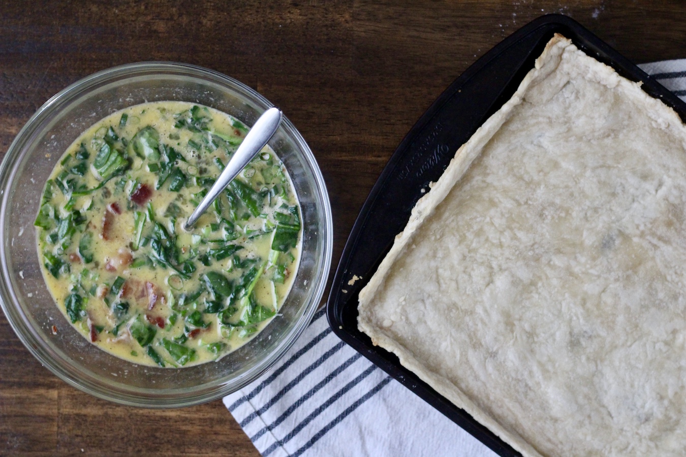 Pre-baked quiche crust with a bowl of the egg mixture to the side.