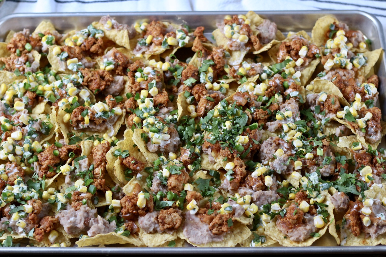 Loaded nachos on a sheet pan.
