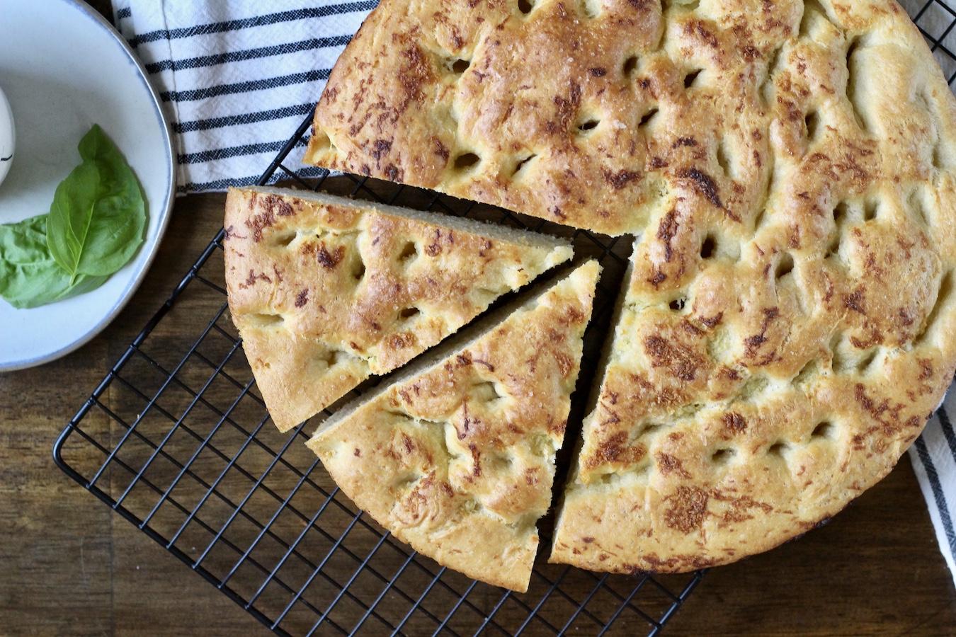 Skillet garlic focaccia on a cooling rack with two wedges cut in the bread.