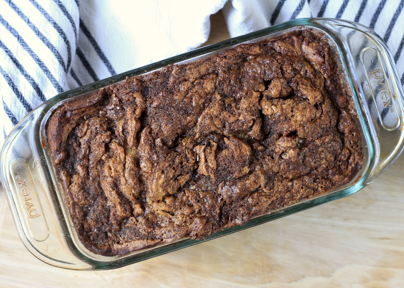 Baked cinnamon swirl banana bread in a bread pan on a wooden counter.