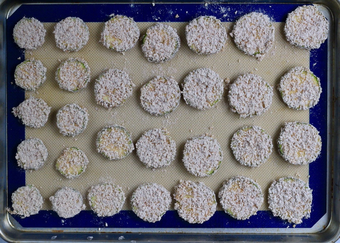 A baking sheet covered in unbaked zucchini bites.